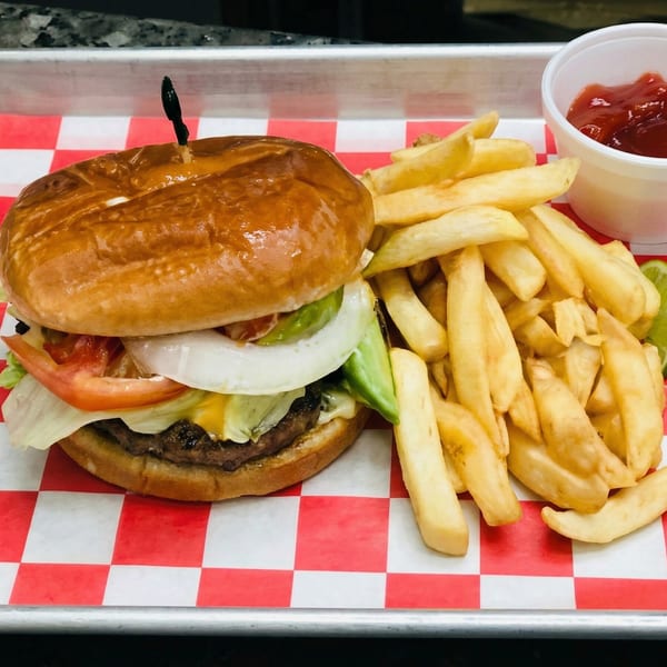 A juicy burger with lettuce, tomato, onion, and avocado, served with golden fries and ketchup.