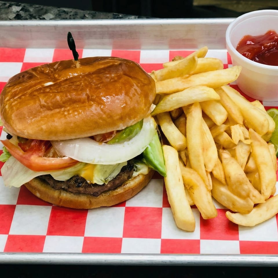 A juicy burger with lettuce, tomato, onion, and avocado, served with golden fries and ketchup.